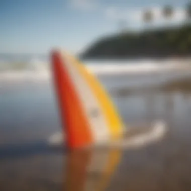 Close-up of surfboard fins on a sandy beach with crystal clear waves in the background