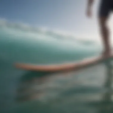 Male surfer standing on surfboard with sandals visible