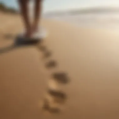 Surfer walking barefoot on a sandy beach carrying a surfboard