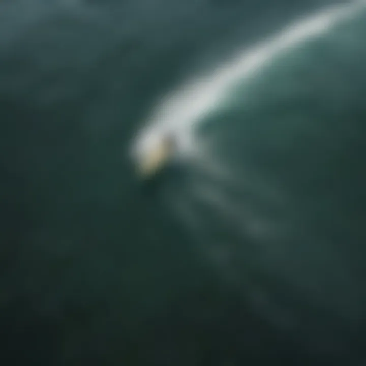 Aerial view of a lone surfer catching a wave in Maine's crystal-clear waters