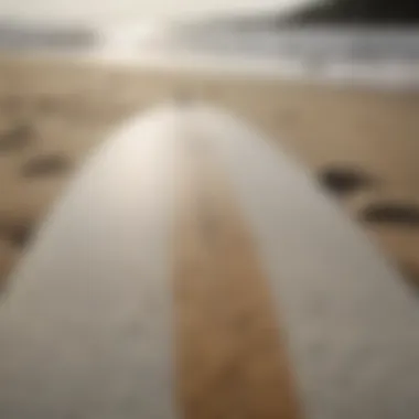 Close-up of a surfboard on a sandy Maine beach with waves in the background